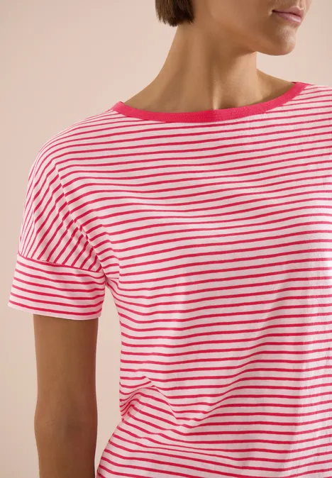 Frau trägt kurzärmliges Shirt mit weißen und pinken Streifen, nur Oberkörper sichtbar