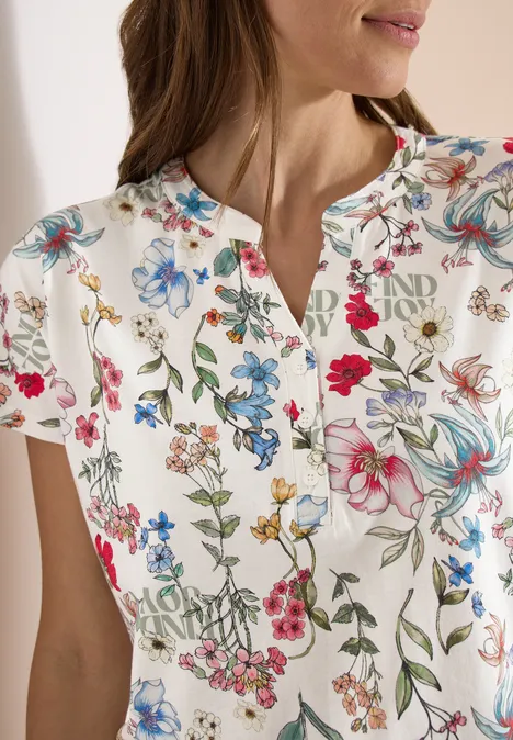 Weißes Kurzarmshirt mit buntem Blumenmuster und kleinem Schlitz am Rundhalsausschnitt.