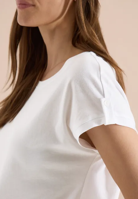 Seitliche Ansicht einer Frau in schlichtem weißen T-Shirt vor hellem Hintergrund.