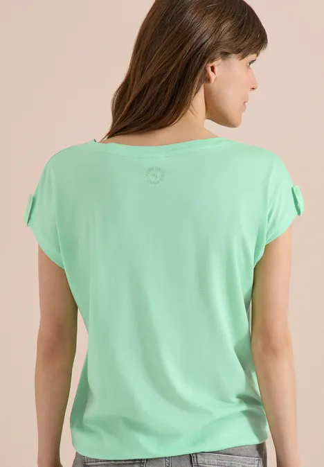 Frau von hinten in mintgrünem T-Shirt mit kurzen, locker fallenden Ärmeln, lange braune Haare.