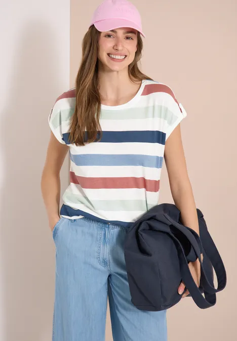 Frau in gestreiftem T-Shirt, weiten Jeanshosen und dunkelblauer Umhängetasche.