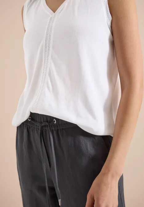 Witte mouwloze top en zwarte broek met koord, casual stijl.