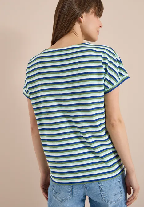 Frau steht mit dem Rücken zur Kamera, trägt ein gestreiftes Kurzarmshirt und Jeans.