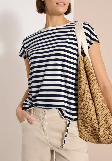 Vrouw met marinewit gestreept T-shirt, beige broek en grote strozak.