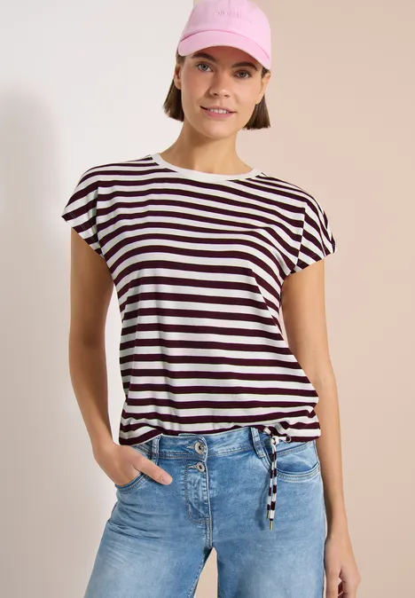 Frau trägt gestreiftes T-Shirt mit Knotendetail, Jeanshose und rosa Kopftuch, Gesicht unkenntlich.