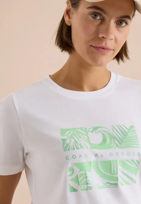 Weißes T-Shirt mit grünem tropischem Blattprint und Schriftzug "Coastal Gardens".