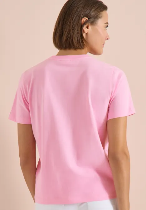Rückenansicht einer Person in einem schlichten rosa T-Shirt vor hellem Hintergrund.