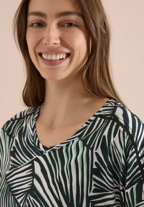 Eine Frau trägt ein grünes, schwarz-weiß gestreiftes Top mit Zebra-Muster.