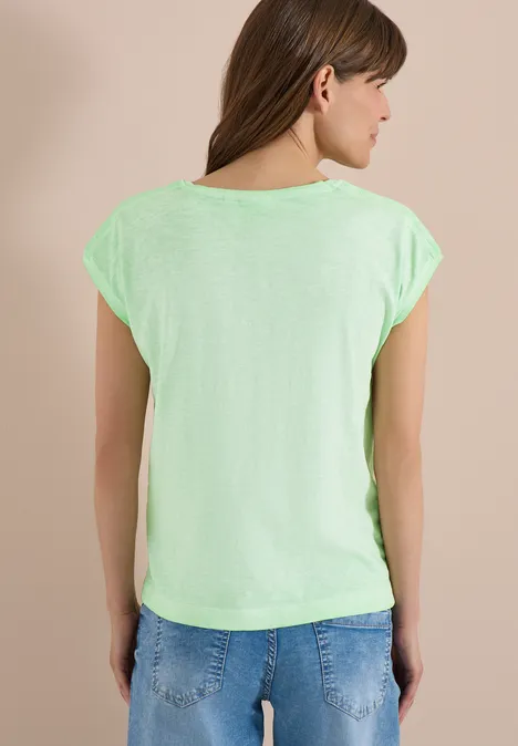 Rückansicht einer Frau in leuchtend grünem T-Shirt vor hellem Hintergrund.