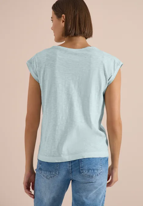 T-Shirt aus Jersey im Garment Dye Look crystal mint Eine Frau von hinten in hellgrauem T-Shirt und blauer Jeans vor hellem Hintergrund.