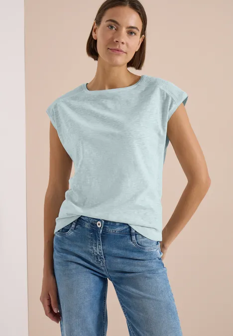 T-Shirt aus Jersey im Garment Dye Look crystal mint Eine Person vor hellem Hintergrund in hellblauem T-Shirt und Jeans, die Arme hinter dem Rücken verschränkt.