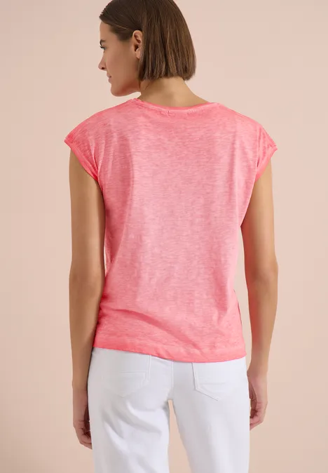 T-Shirt aus Jersey im Garment Dye Look coral Eine Frau von hinten mit pinkem T-Shirt und weißen Jeans vor hellem Hintergrund.