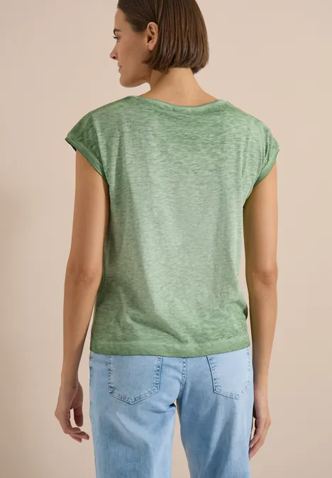 Een vrouw van achter gefotografeerd draagt een groen t-shirt en blauwe jeans.