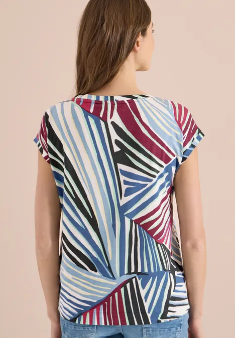 Frau von hinten in bunt gestreiftem, grafischem Kurzarmtop in Blau, Schwarz, Weiß, Rot und Grün.