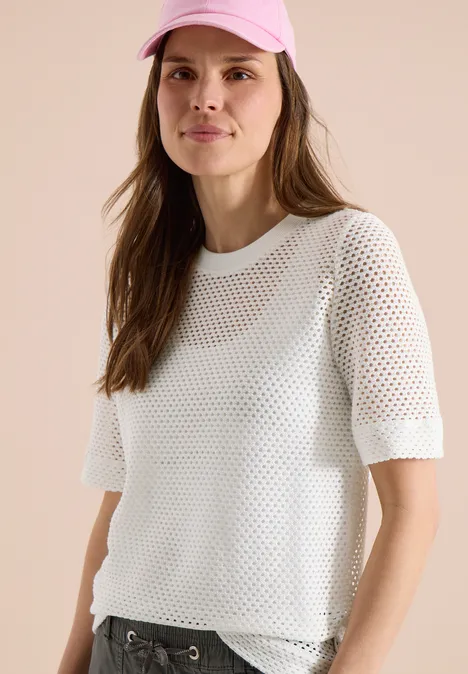 Modell mit langen braunen Haaren in weißem, halbtransparentem Netzshirt mit kurzen Ärmeln.