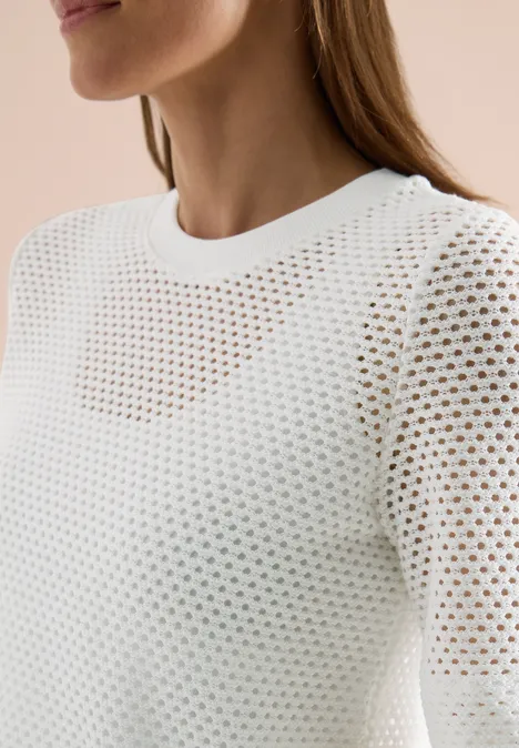 Weißes, locker gestricktes Oberteil mit rundem Ausschnitt und feinem Lochmuster.