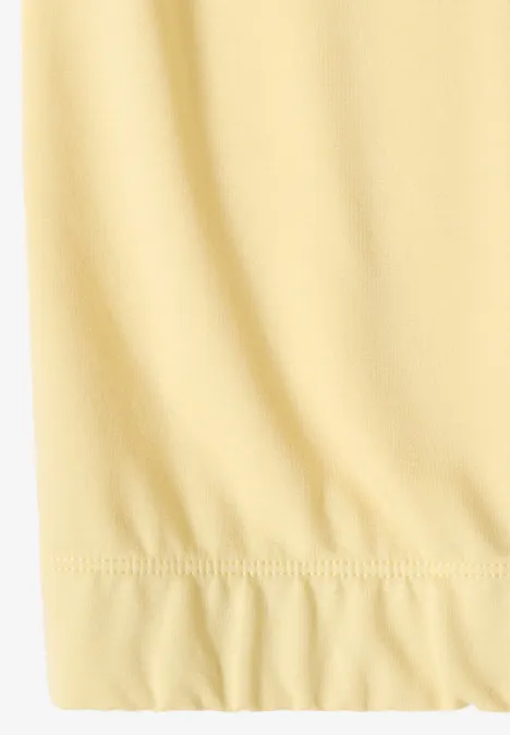 Nahaufnahme eines hellgelben, leicht gerafften Stoffsaums.