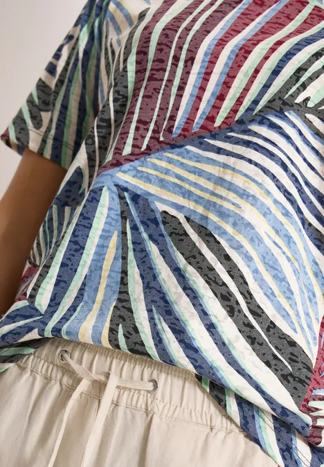 Gros plan d'un torse vêtu d'un t-shirt rayé coloré et d'un pantalon beige à taille élastique.