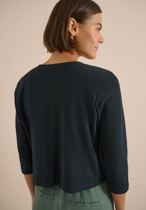 Rückansicht einer Person mit kurzem Bob und dunkelgrünem Cardigan mit 3/4-Ärmeln.