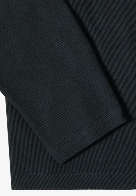 Nahaufnahme eines langärmligen Oberteils aus strukturiertem schwarzen Stoff.