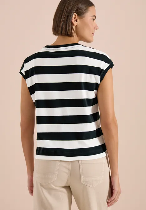 Vrouw van achteren in zwart-wit gestreept T-shirt met korte mouwen en beige broek