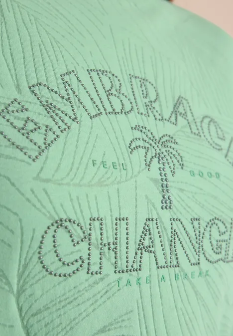 Grünes T-Shirt mit Strassschrift 'EMBRACE CHANGE', Palme in der Mitte und kleinem 'FEEL GOOD'-Schriftzug.