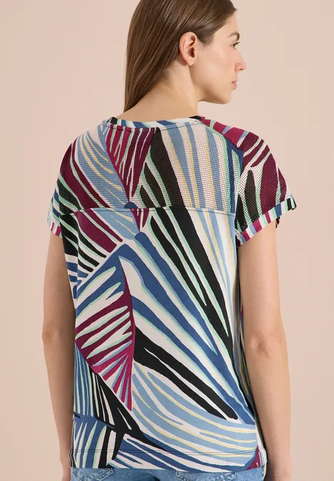 Frau von hinten in buntem, gestreiftem Kurzarmshirt mit abstraktem Streifenmuster.