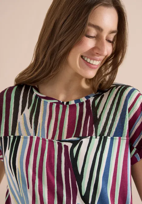 Frau trägt kurzärmeliges Top mit bunten vertikalen Streifen.