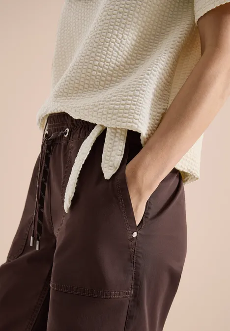 Damesoutfit met lichtbeige, gestructureerde top en losse donkerbruine broek met zakken