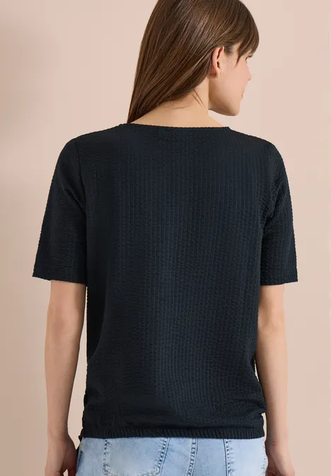 Rückenansicht einer Frau in schwarzem T-Shirt und blauer Jeans.