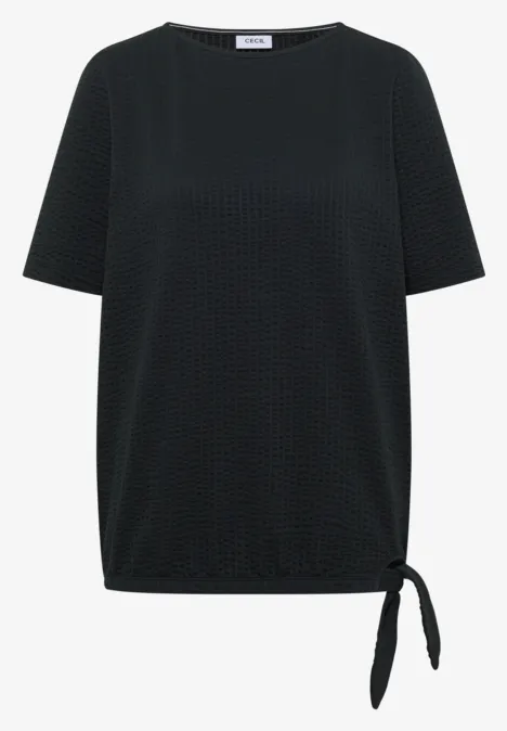 Schwarzes Damenshirt mit strukturiertem Punktmuster, kurzen Ärmeln und seitlichem Knotendetail am Saum.