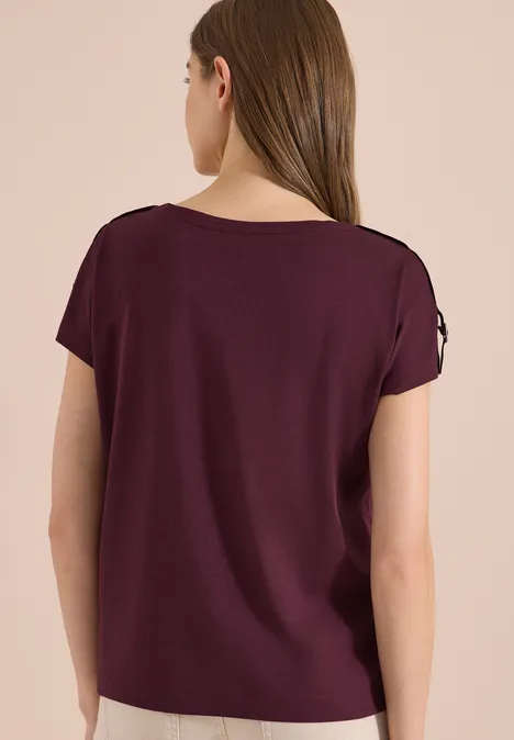 Vrouw van achteren in een eenvoudig donkerpaars T-shirt met korte mouwen.