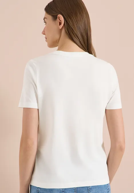 Frau in schlichtem weißen T-Shirt, Rückenansicht vor neutralem Hintergrund.