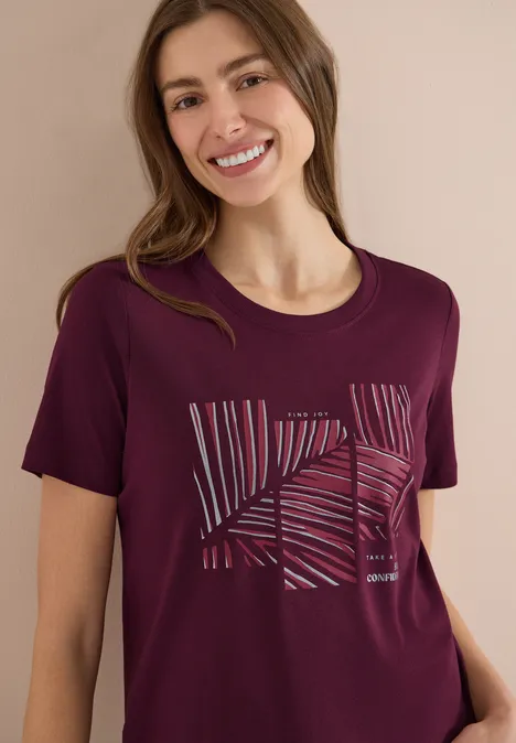 Frau trägt lila T-Shirt mit abstraktem, gestreiftem Linienmuster auf der Brust.