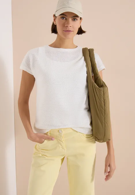 T-Shirt mit Boatneck im Ajour-Look vanilla white Frau trägt weißes T-Shirt, hellgelbe Jeans und grüne Umhängetasche vor neutralem Hintergrund.