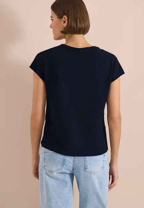 T-Shirt mit Boatneck im Ajour-Look universal blue Frau von hinten in dunkelblauem T-Shirt und hellblauen Jeans vor beiger Wand.