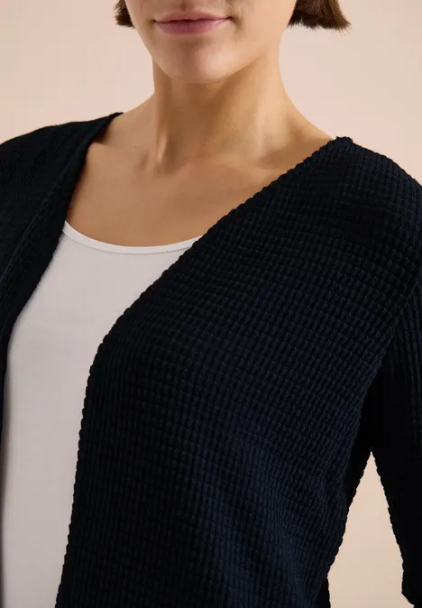 Offene 3/4-Arm Jacke im Ajour-Look universal blue Frau trägt schwarzen Strick-Cardigan über weißem Top, nur Oberkörper sichtbar.