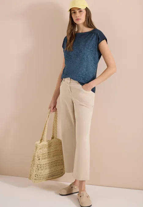 Shirt met boothals in garment-dye look universal blue Vrouw in blauw shirt, beige broek en espadrilles met gevlochten tas voor lichte achtergrond.