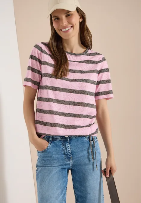 T-Shirt in Ausbrenner-Optik raw khaki Frau trägt rosa-schwarz gestreiftes T-Shirt und blaue Jeans, steht lässig mit Hand in Tasche.
