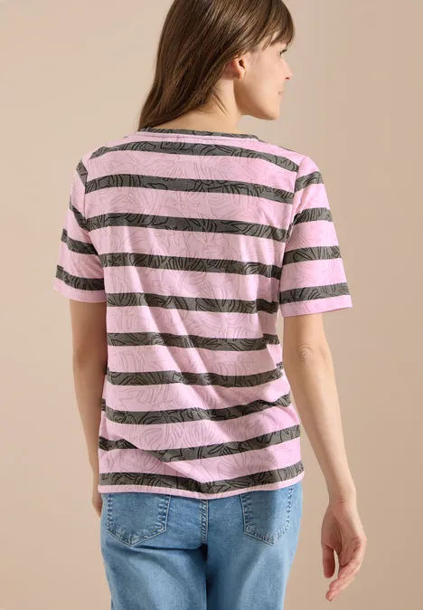 T-Shirt in Ausbrenner-Optik raw khaki Eine Frau in rosa-braun gestreiftem T-Shirt und Jeans, von hinten vor beiger Wand stehend.