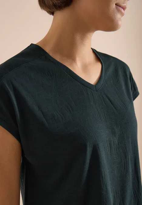 Shirt met ton-sur-ton burn-outpatroon palm breeze green Vrouw draagt donker groen T-shirt met V-hals, torso schuin in beeld.