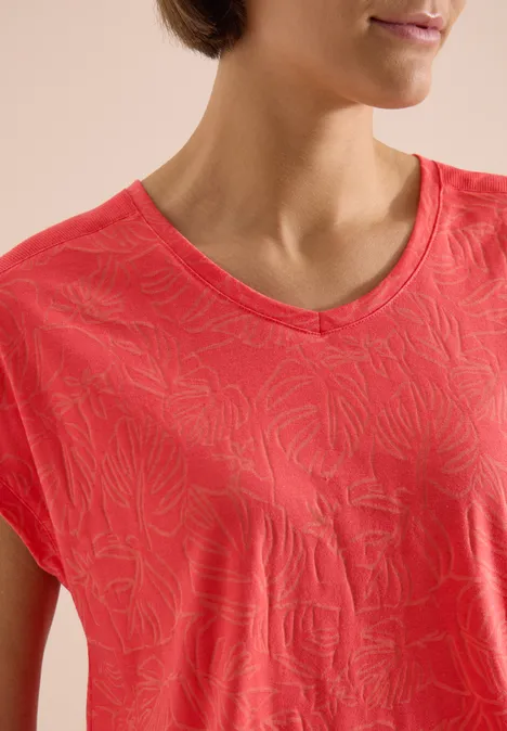 Frau in rotem T-Shirt mit V-Ausschnitt und dezentem Allover-Muster