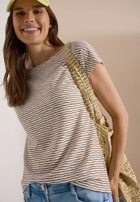 Femme en t-shirt rayé et jean, portant un sac crocheté à l'épaule.