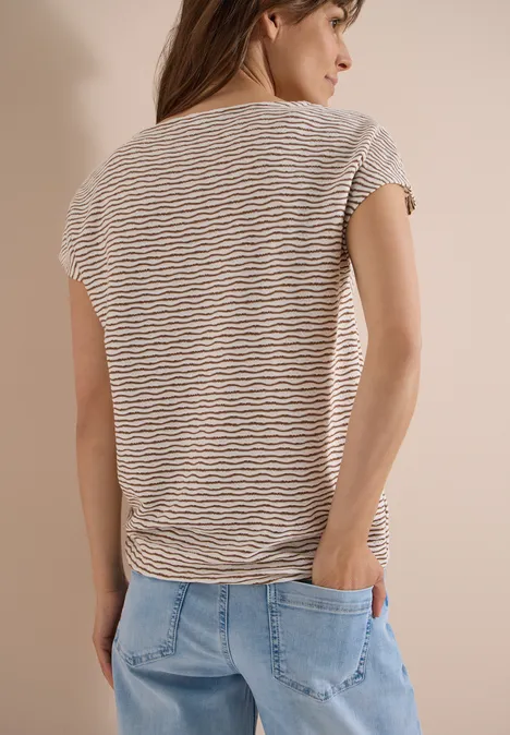 Femme de dos en tee-shirt rayé et jean, les mains dans les poches.