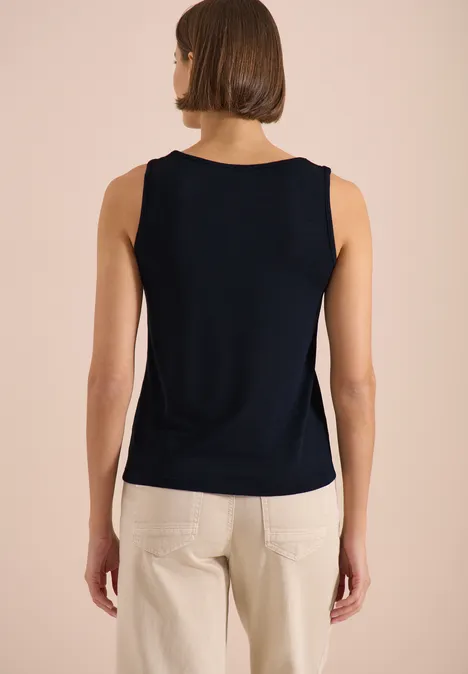 Top met ronde V-hals en gevlochten detail universal blue Vrouw van achteren met een donkerblauw mouwloos topje en een lichte broek