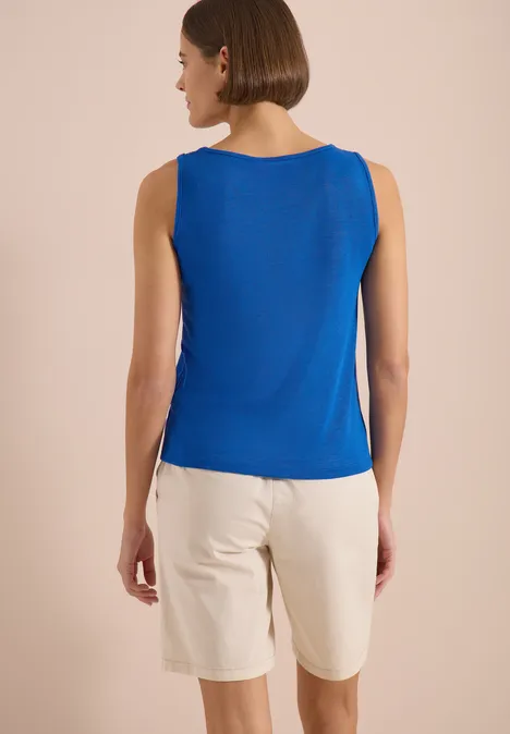 Top avec col en V arrondi et détail tressé surf blue Femme de dos portant un débardeur bleu et un short clair sur fond neutre.