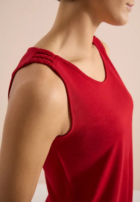 Top avec col en V arrondi et détail tressé tamarillo red Débardeur rouge sans manches avec bretelles tressées et encolure arrondie, gros plan.