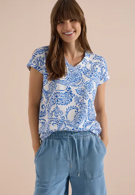 T-Shirt mit V-Neck und Print vanilla white Frau trägt kurzärmliges blau-weißes Mustershirt und lockere hellblaue Hose mit Taschen und Tunnelzug.