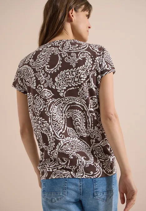 T-Shirt mit V-Neck und Print brown cacao Frau von hinten in braun-weiß gemustertem T-Shirt im Paisley-Design und blauen Jeans.
