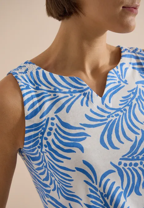 Haut sans manches blanc à motifs feuilles bleues, vu de face sur le buste.